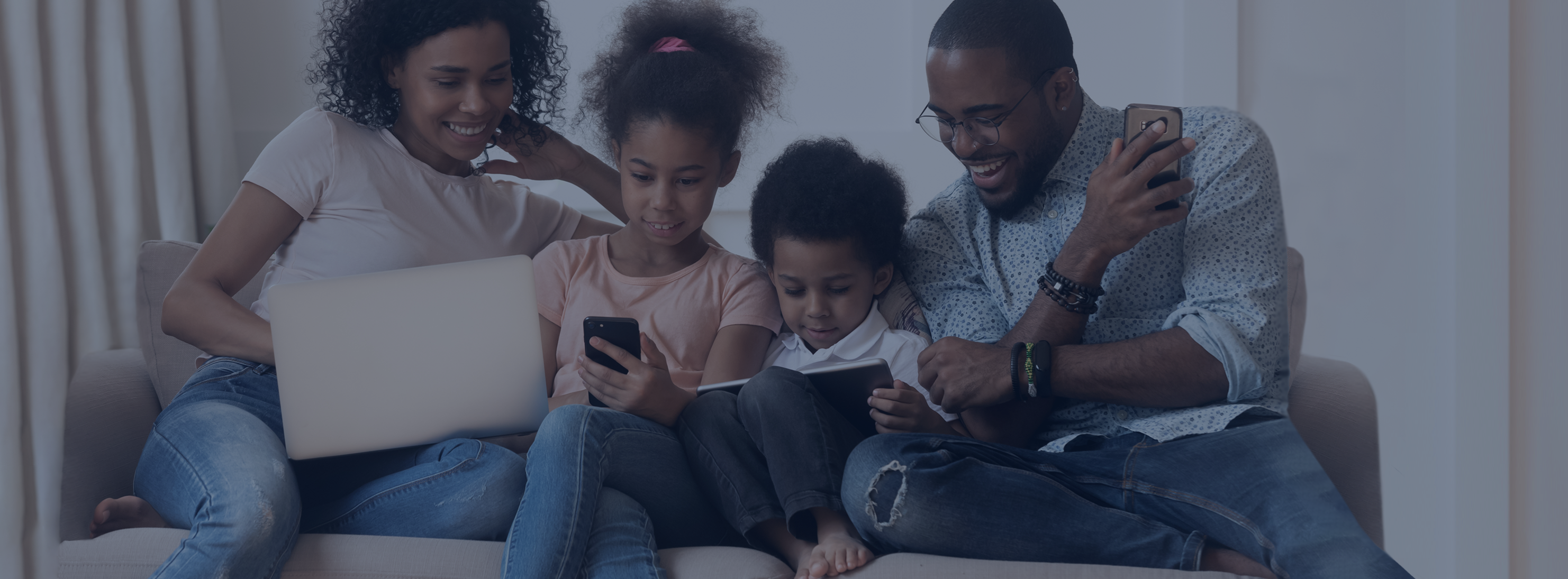 Famille réunie autour de la technologie et des tablettes sur un canapé - Portail des parents